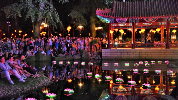 Ogród Chiński w Łazienkach wieczorem, oświetlony latarniami, wokół stoją ludzie i słuchają muzyki.