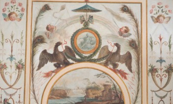 Grafika przedstawiająca dwa ptaki trzymające w dziobach wieniec laurowy, okalający medalion z przedstawieniem kobiety, po bokach znajdują się pawie pióra, amorki oraz ptaki, poniżej widać pejzaż z krajobrazem nad rzeką.