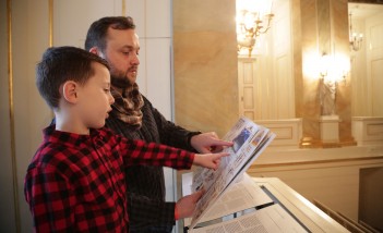 Mężczyzna z chłopcem oglądają ilustrowaną książkę. 