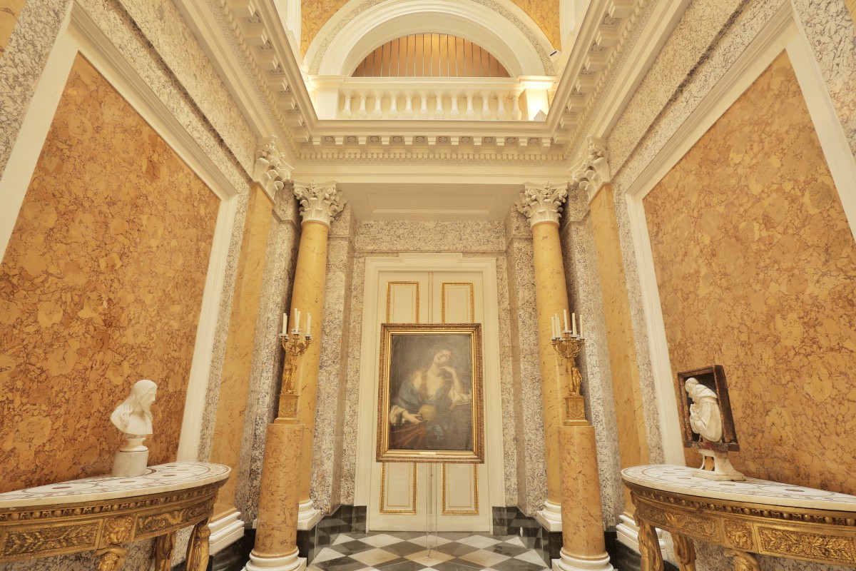 Kaplica w Pałacu na Wyspie. Pokój dwie kolumny, pośrodku wisi obraz, po bokach półokrągłe stoliki, na których stoją rzeźby. 