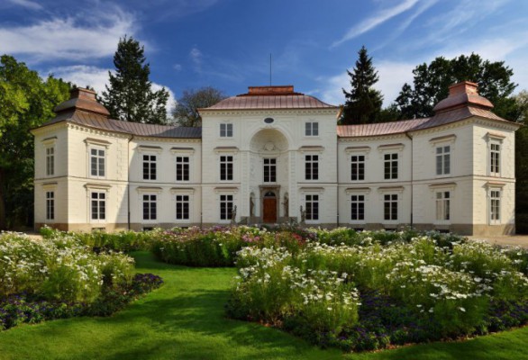 Pałac Myślewicki z fronu, w otoczeniu zieleni.