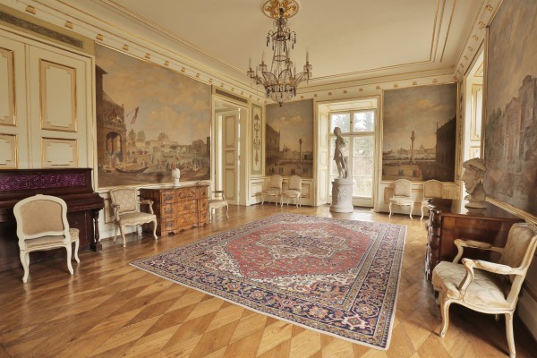 Sala Stołowa w Pałacu Myślewickim, pośrodku leży dywan, po ścianami stoją komody i krzesła, pod oknem na środkowej ścianie stoi rzeźba przedstawiająca kobietę.
