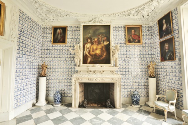 Pokój Bachusa w Pałacu na Wyspie. Na środku znduje się kominek, nad którym wiszą obrazy, po obu stronach kominka stoją wazy i rzeźby, po prawej stronie, po ścianą, stoi krzesło.