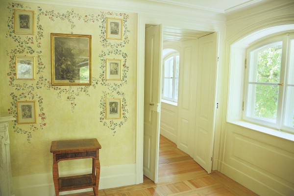 Pomieszczenie ze stolikiem, na ścianach wiszą obrazy.