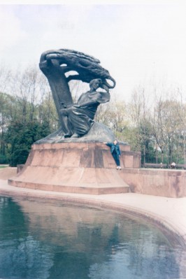 Pomnik Chopina w Łazienkach Królewskich, pod którym stoi dziecko. 