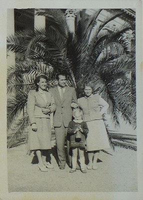 Dwie kobiety, mężczyzna i dziewczyna stoją pod palmą.