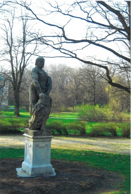 Rzeźba przedstawiająca mężczyznę z lew, stojąca w ogrodzie.