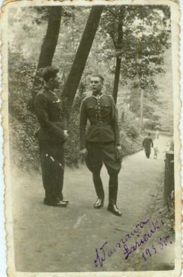 Dwóch mężczyzn w mundurach wojskowych stoi na parkowej alejce.