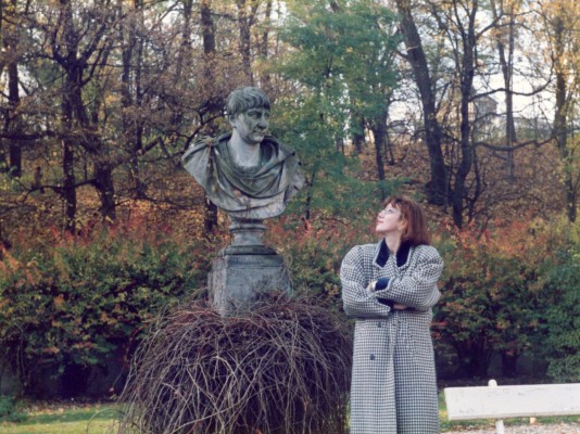 Kobieta w parku, stoi przy rzeźbie.