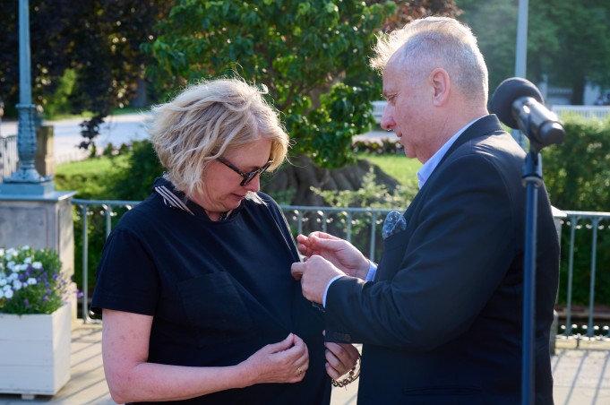 Mężczyzna przypina kobiecie do sukienki odznaczenie.