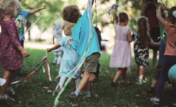 Dzieci bawiące się w parku kolorowymi taśmami.