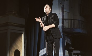 Mężczyzna stoi na scenie i gestykulując, śpiewa.
