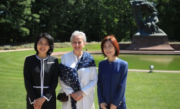 Trzy kobiety stoją w parku i pozują do zdjęcia.