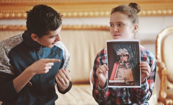 Dziewczynka trzyma obrazek, chłopiec siedzący z boku wskazuje na obrazek placem.