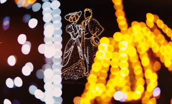 Iluminacja w Łazienkach Królewskich, widoczne są świetliste postaci kobiety i mężczyzny w strojach z epoki.