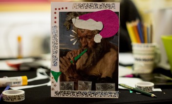Kartka świąteczna wykonana kolażem - Satyr grający na flecie ma na głowie czapkę świętego Mikołaja.