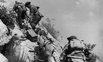 Żołnierze z czasów II wojny światowej wspinający się na wzgórze.