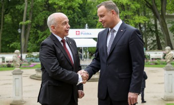 Prezydent Szwajcarii i prezydent Polski stoją i ściskają sobie dłonie.