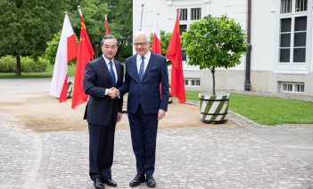 Minister Wang Yi i minister Jacek Czaputowicz stoją przed Pałacem Myślewickim i ściskają sobie dłonie.