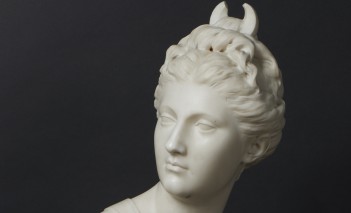 Rzeźba przedstawiająca popiersie antycznej bogini Diany, wykonana z marmuru, ukazana na na ciemnym tle.