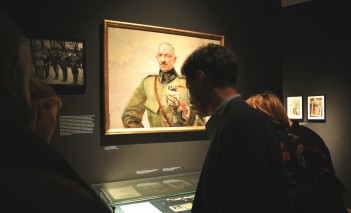 Wystawa "Virtuti Militari" Kilka osób stoi przed szklaną gablotą i ogląda pamiątki.