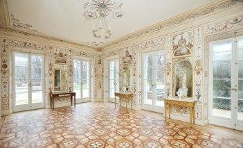 Pomieszczenie w Białym Domu, pod oknami stoją stoliki, na których eksponowane są rzeźby.