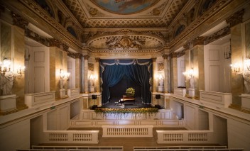 Wnętrze Teatru Królewskiego w Starej Oranżerii, widoczna jest scena, na której stoi fortepian.