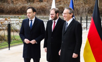 Trzech mężczyzn w czarnych płaszczach stoi obok siebie i pozuje do zdjęcia.