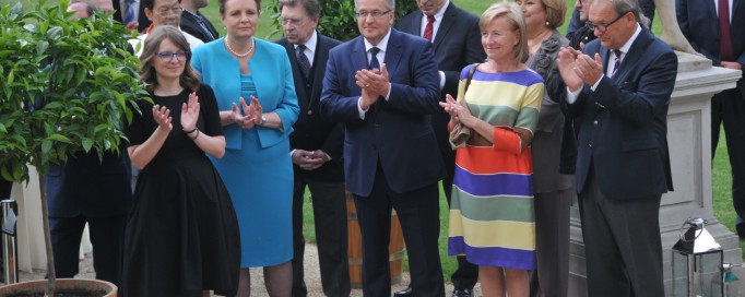 Grupa osób, kobiet i mężczyzn, stoi i bije brawo.