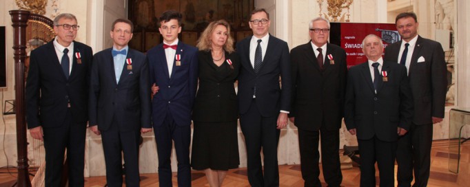 Grupa kilku osób z orderami przypiętymi do piersi stoi i pozuje do zdjęcia.