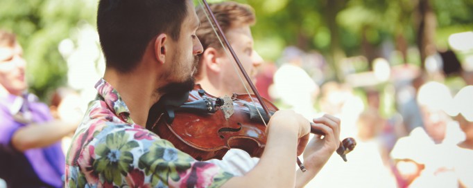 Mężczyzna grający na skrzypcach w plenerze.