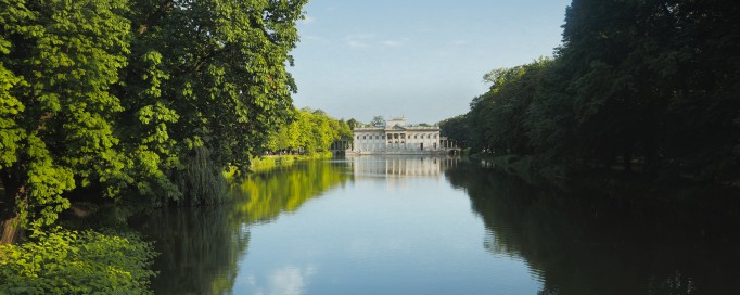 Widok na Pałac na Wyspie w otoczeniu zieleni i wody.