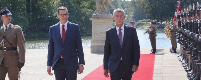 Premier Morawiecki i premier Babisz idą po czerwonym dywanie, po lewej i prawej stronie stoją żołnierze pełniący wartę honorową.
