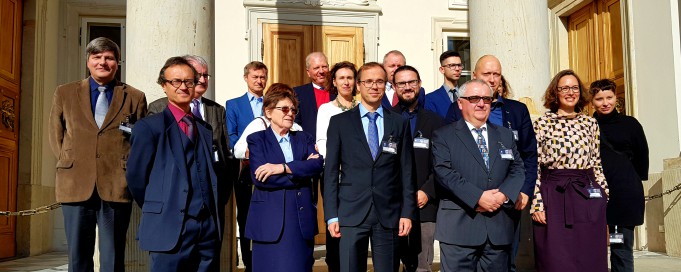 Grupa osób stoi przed wejściem do Płacu na Wyspie, odwrócona tyłem do pałacowych kolum, tuż przy drzwiach.