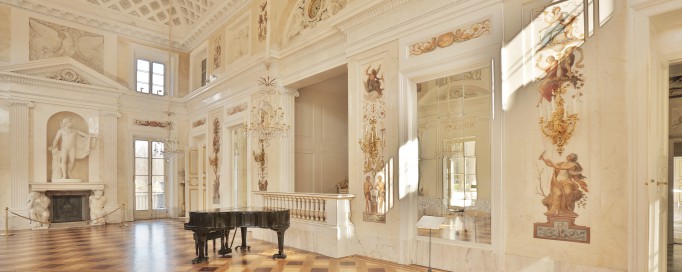 Sala Balowa w Pałacu na Wyspie, ściany zdobią malowidła i rzeźby, w pomieszczeniu stoi fortepian.