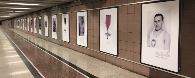 Plansze wystawowe wiszące na ścianie, na pierwszej z nich widać portret mężczyzny.