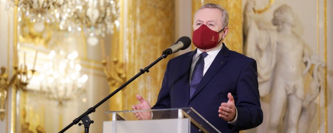 Minister kultury na konferencji prasowej, przemawiający przed mikrofonem. 