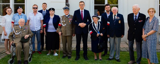 Grupa powstańców pozuje do zdjęcia na tle fasady Pałacu Myślewickiego.