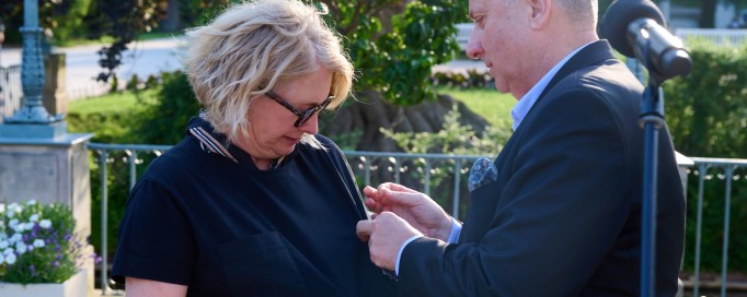 Mężczyzna przypina kobiecie do sukienki odznaczenie. 
