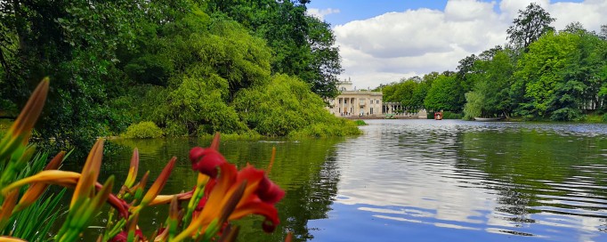 Pałac na Wyspie w otoczeniu wody i drzew.