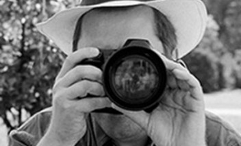 Mężczyzna w kapeluszu robi zdjęcie aparatem fotograficznym.