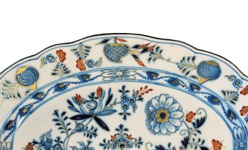 Fragment porcelanowego talerza, ozdobionego kwiatami i gałązkami. 