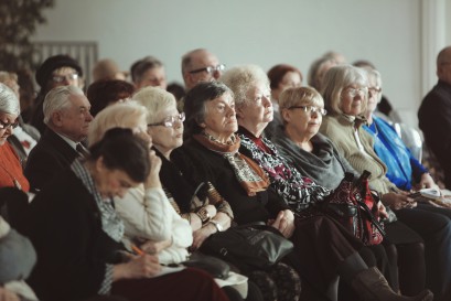 Grupa starszych osób siedzi i słucha wykładu.
