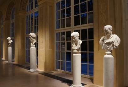Rzeźby przedstawiające męskie popiersia stoją na kolumnach pod oknami sali wystawowej.