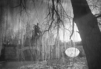 Archiwalne zdjęcie przedstawiające pomnik jeźdźca na koniu, stojący na moście na tle drzew.