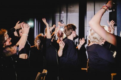 Grupa ludzi z uniesionymi w górze rękami. 