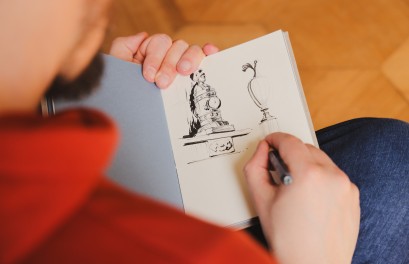 Osoba siedząca tyłem i rysująca elementy pomnika.