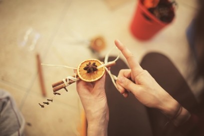 Kobieca ręka trzymająca laskę cynamonu z plastrem pomarańczy. 