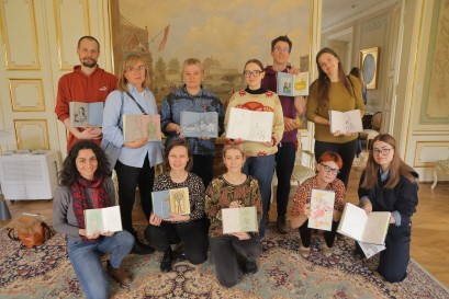 Grupa kilkunastu osób pozuje do zdjęcia, trzymając przed sobą książki. 