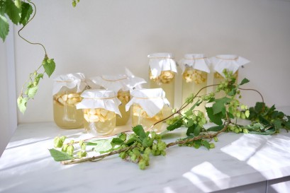 Słoiki z konfiturami stojące na blacie. Przed słoikami leży gałązka z liśćmi. 